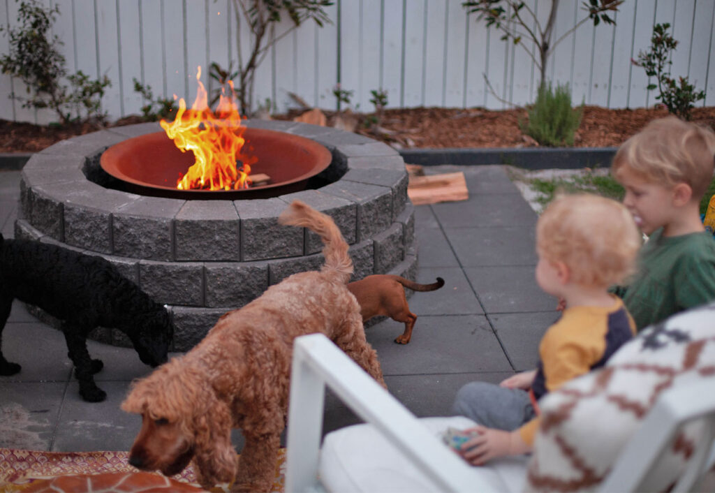Children and dogs gather around a fire pit made using Adbri Masonry Miniwall blocks.