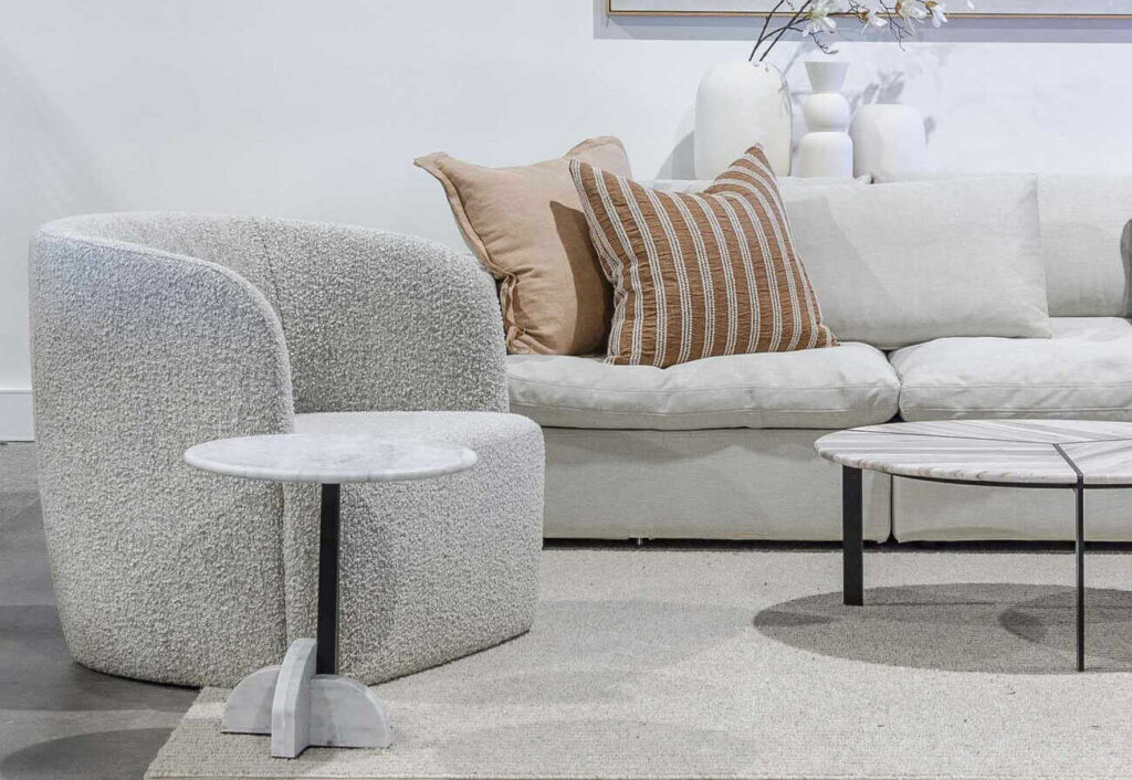 Grey boucle armchair in a lounge room next to a marble-top side table.