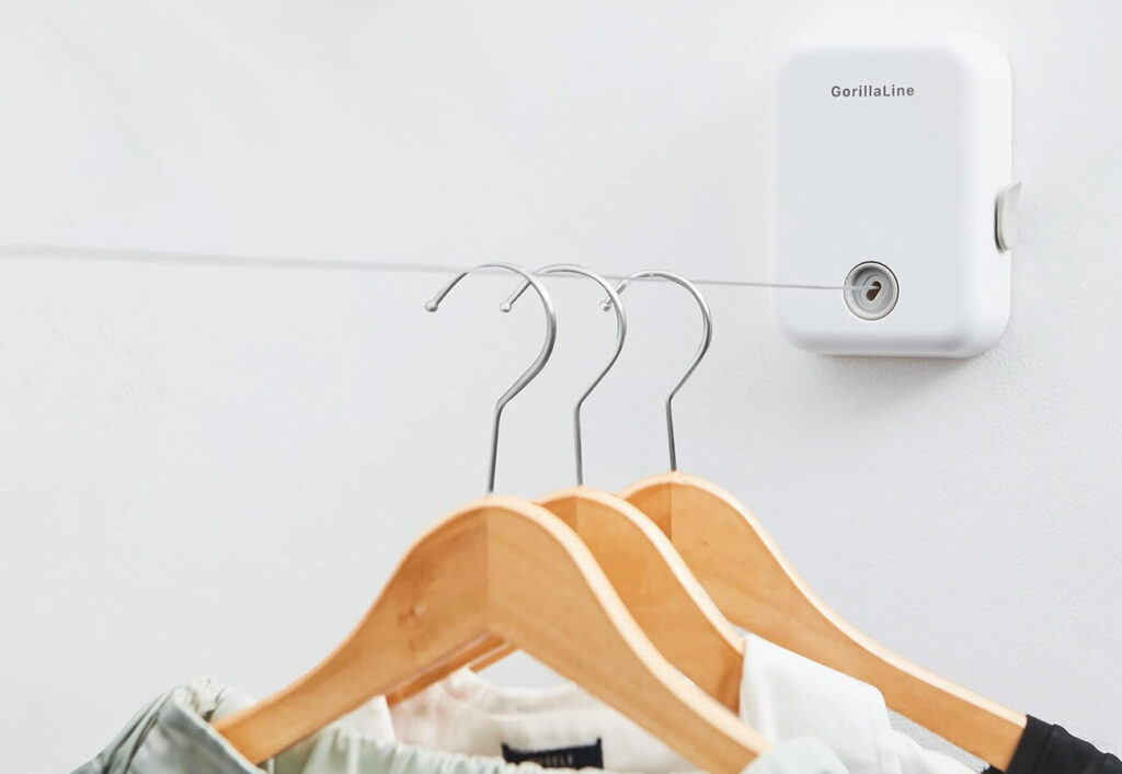 GorillaLine retractable clothesline attached to a wall with three coat hangers hanging from the line.