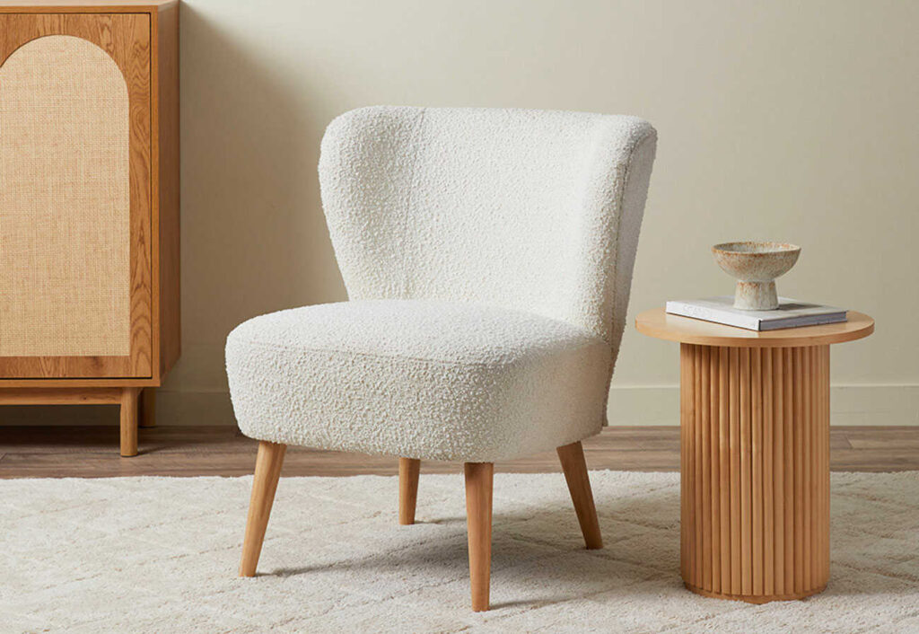 Cream boucle occasional chair next to a timber side table.