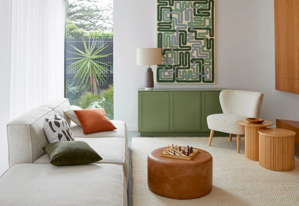 Modern living room with a green buffet, white sofa and tan leather ottoman.