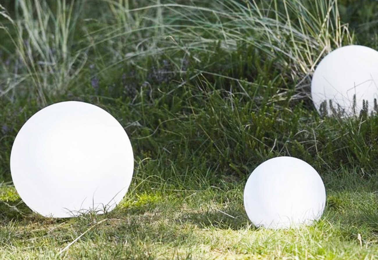 Outdoor solar LED sphere lamps nestled among grass and bushes.