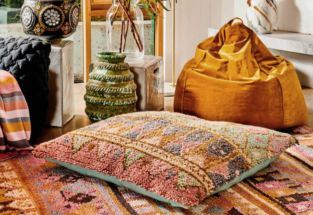 Large cushion on a coloured floor rug.