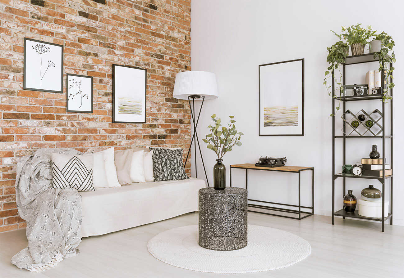 Small living room with a white sofa, black shelving and an exposed brick wall.