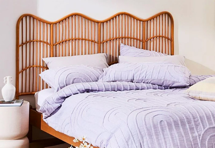 Bed with a honey-coloured rattan bedhead and wooden frame.