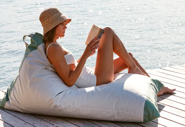 Woman in a bathing suit reading on an outdoor bean bag.