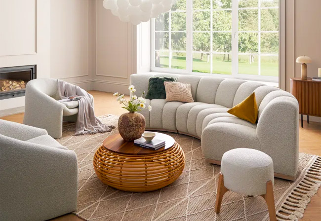 Curved sofa positioned in a living room with two boucle armchairs.