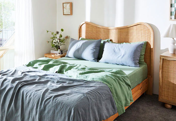 Large bed with curved rattan headboard and blue bed linen.