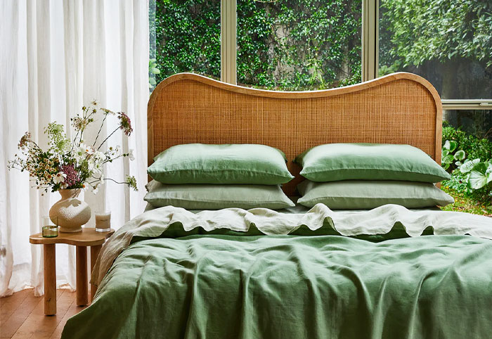 Queen bed with a rattan headboard and green linen.