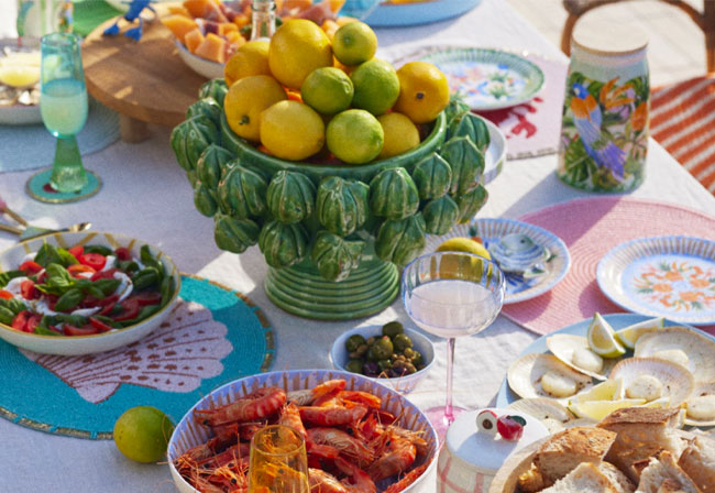 An outdoor table dressed with colourful tableware and a unique centrepiece filled with lemons.
