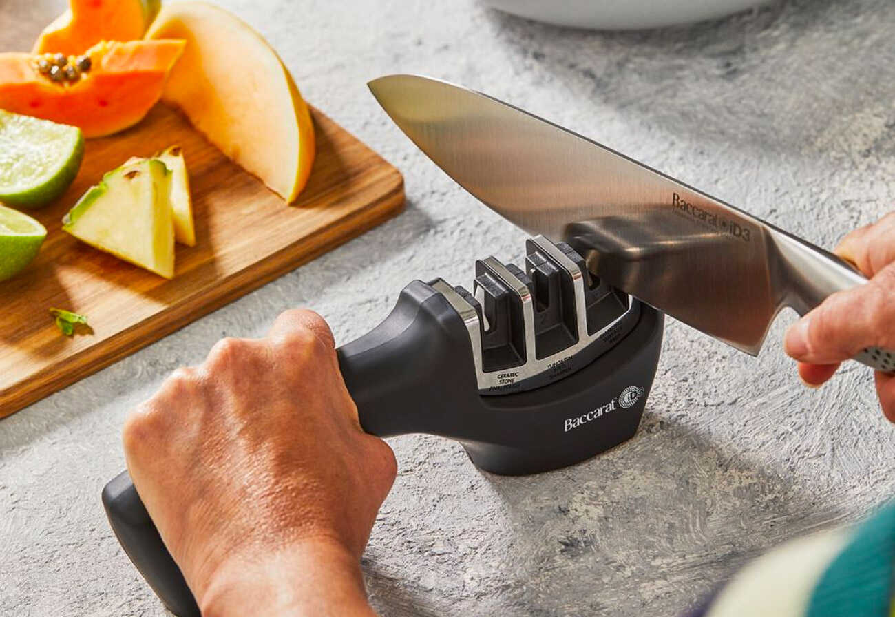 Person using a Baccarat knife sharpener on a kitchen bench.