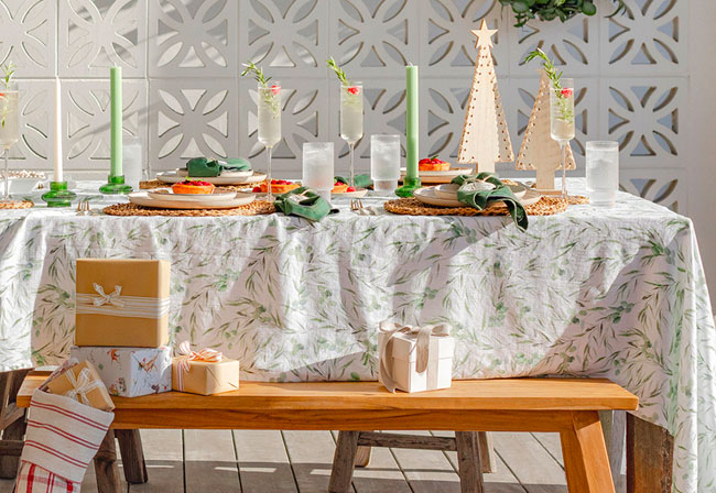 A Christmas table decorated with green candles and napkins.