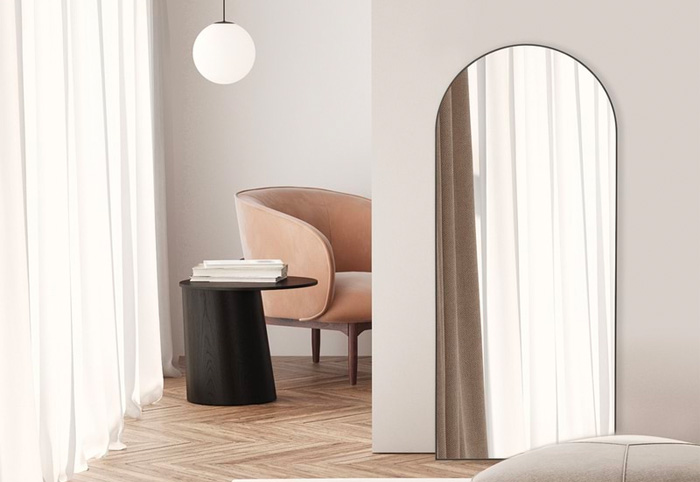 A curved mirror with a black rim leaning against a bedroom wall.