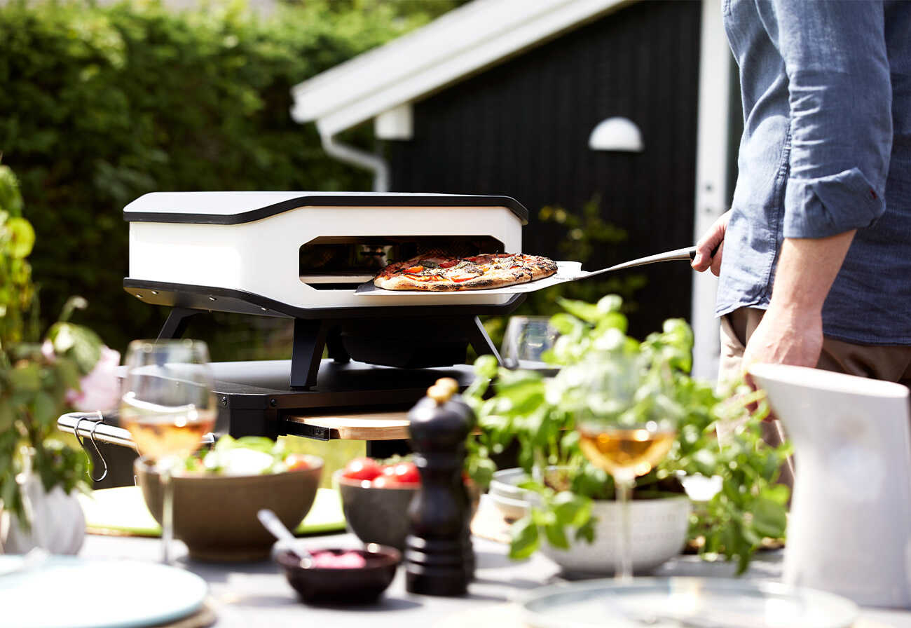 Cozze electric pizza oven being used on an outdoor table.