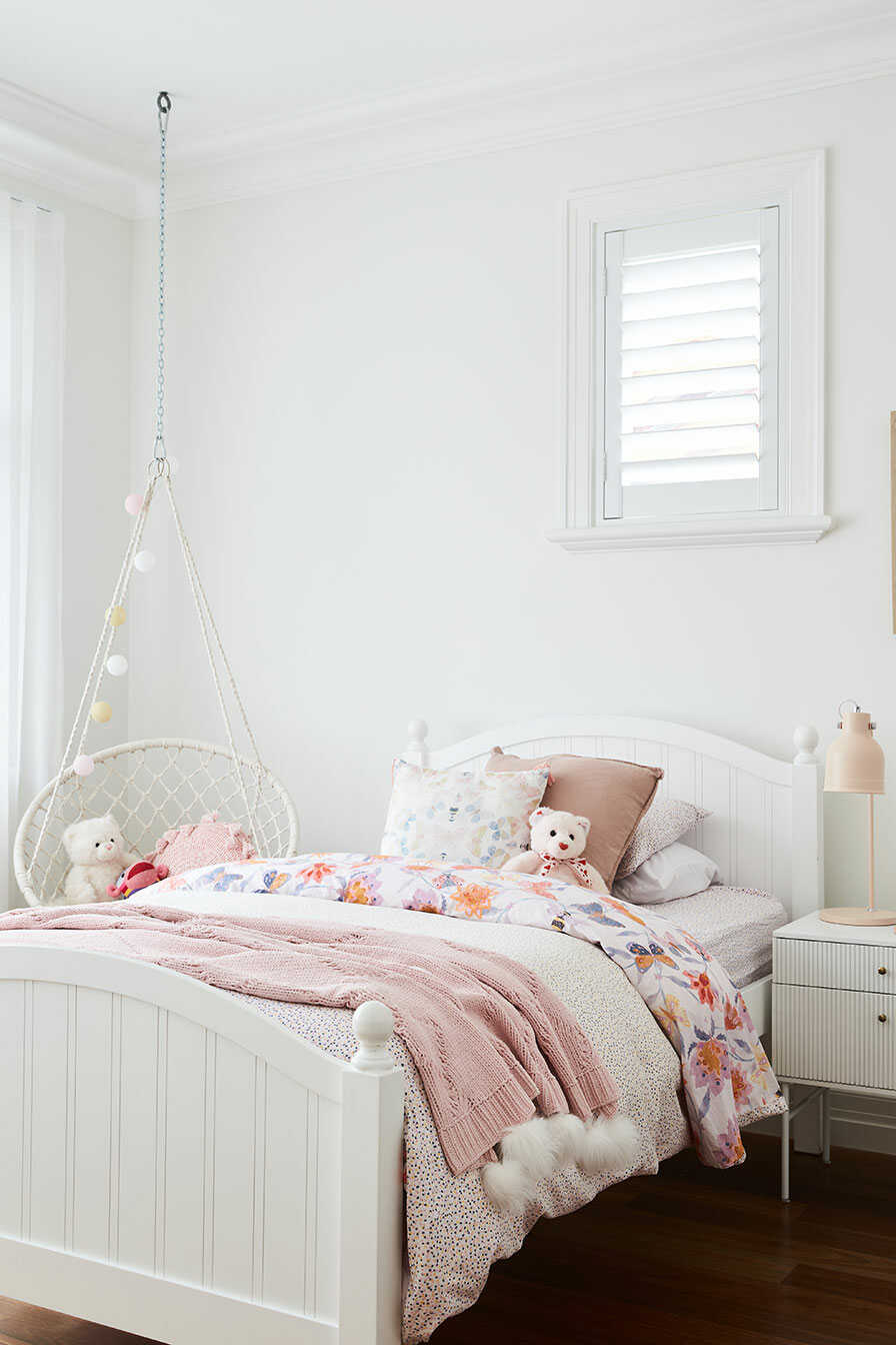 A bright children's room with a single bed and swing chair.
