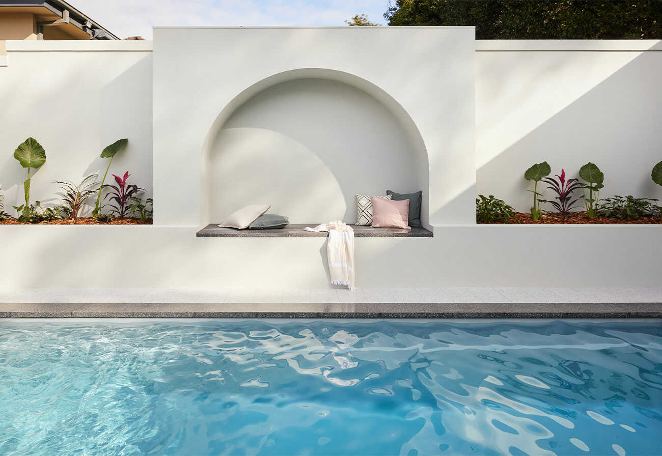 A backyard swimming pool featuring with an arched feature wall.