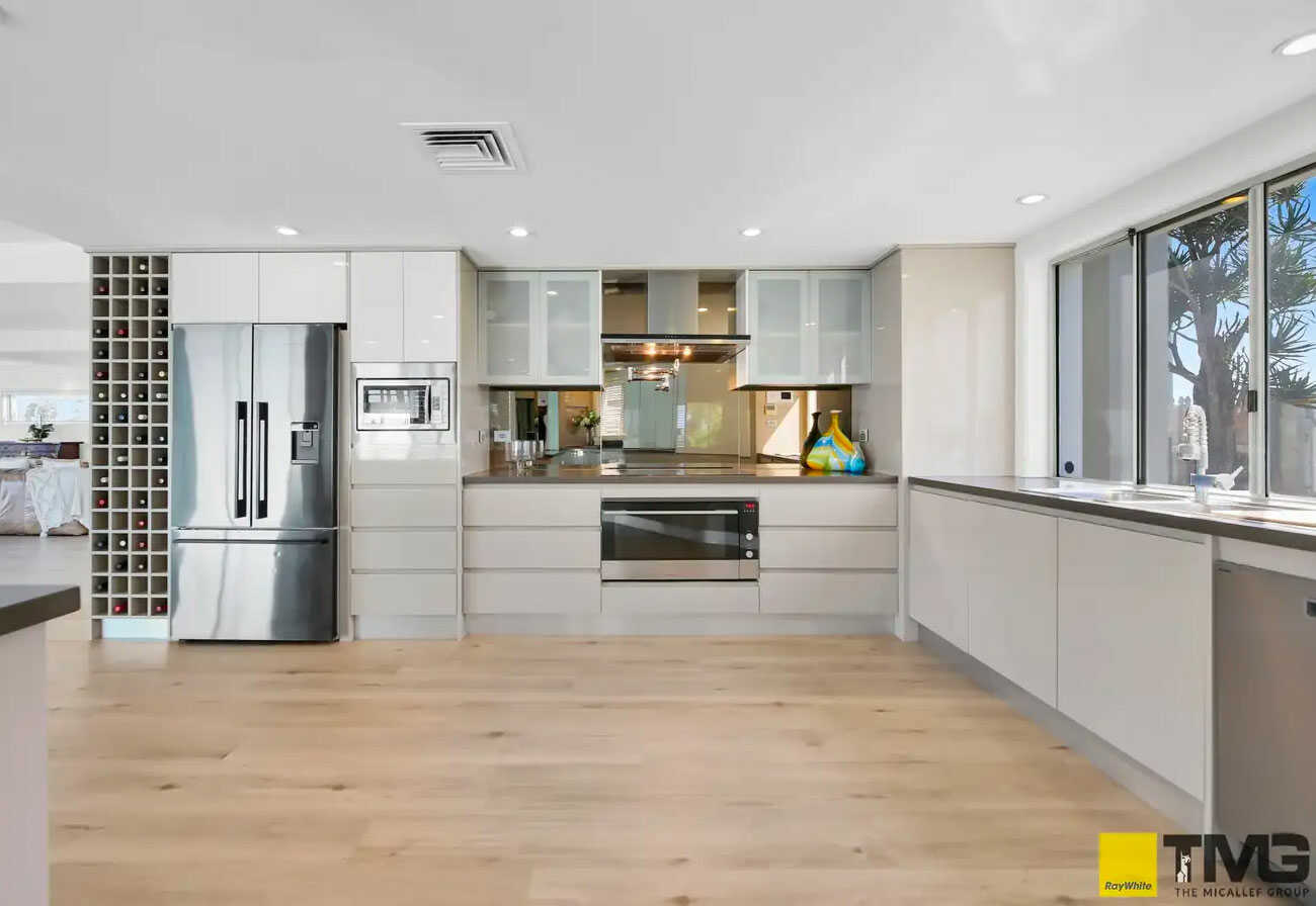 Large modern kitchen with mirror splashback and hug wine storage racks.