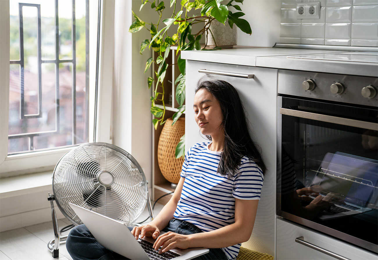 Woman sitting on the flooring in front of a fan.