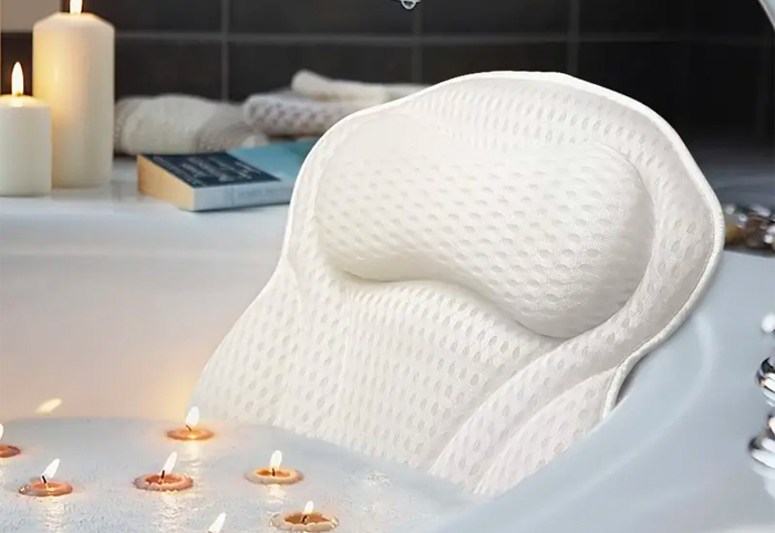 A 4D mesh pillow in a tub with bubbles and floating candles. 