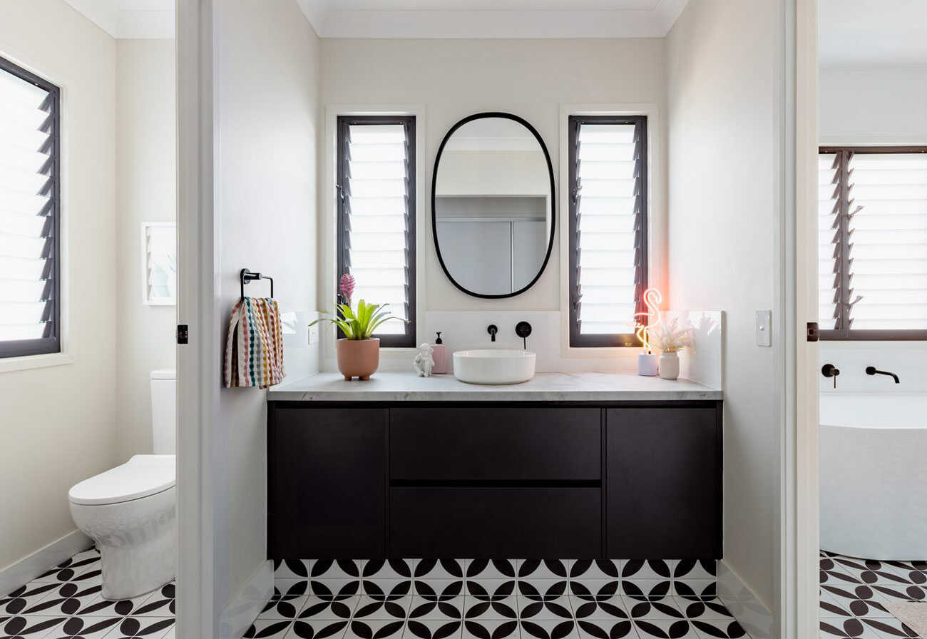 Black and white vanity with toilet and bath on either side.