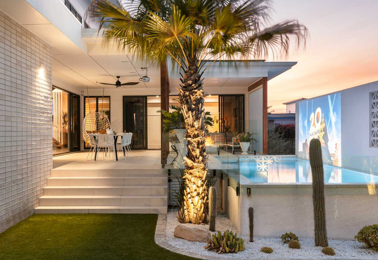 Modern house with a movie projected onto a pool wall.