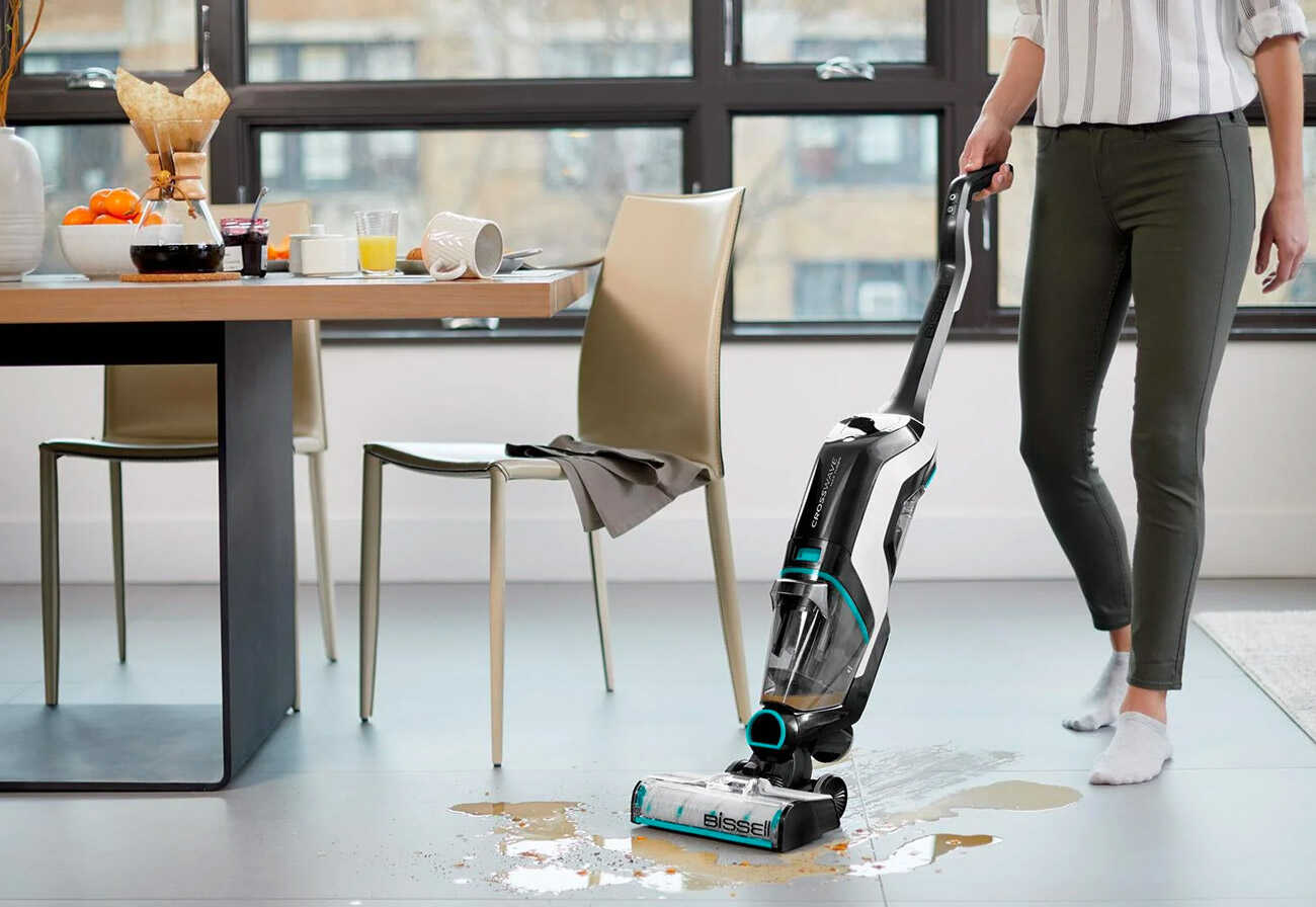 Lady uses a wet and dry vacuum to clean a spill on a kitchen floor.