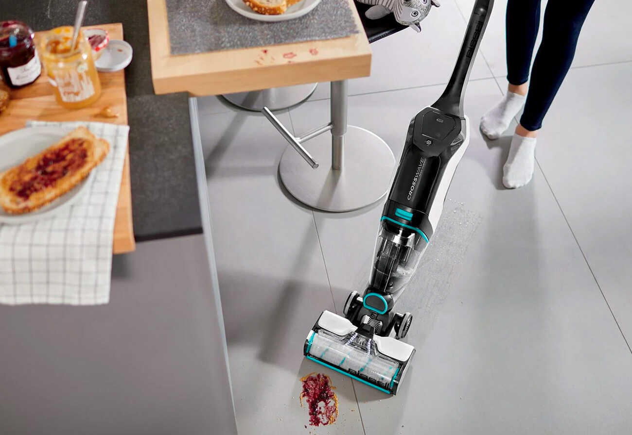 Person vacuuming a wet spill in a kitchen.