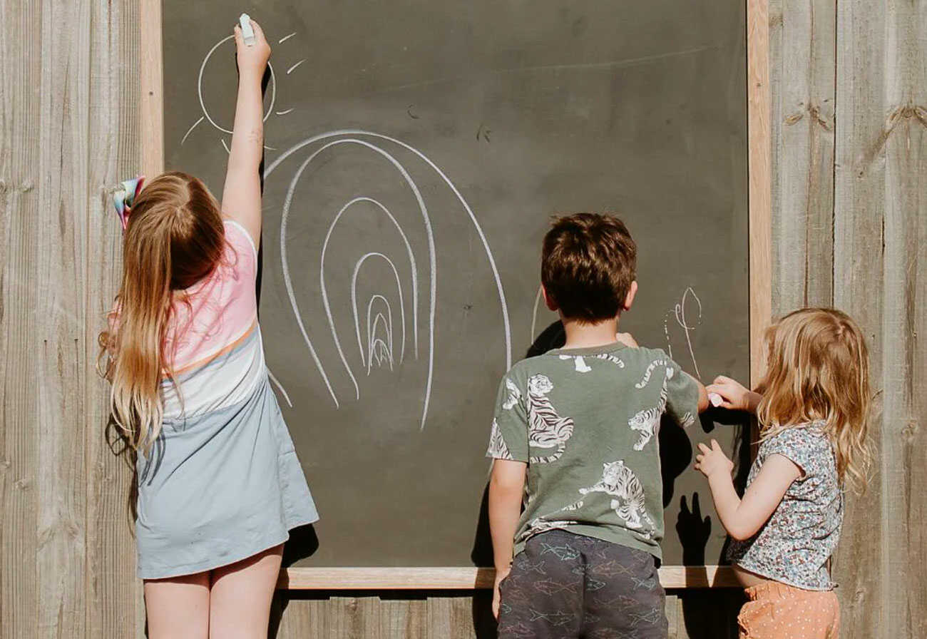 Children drawing on an outdoor chalkboard.