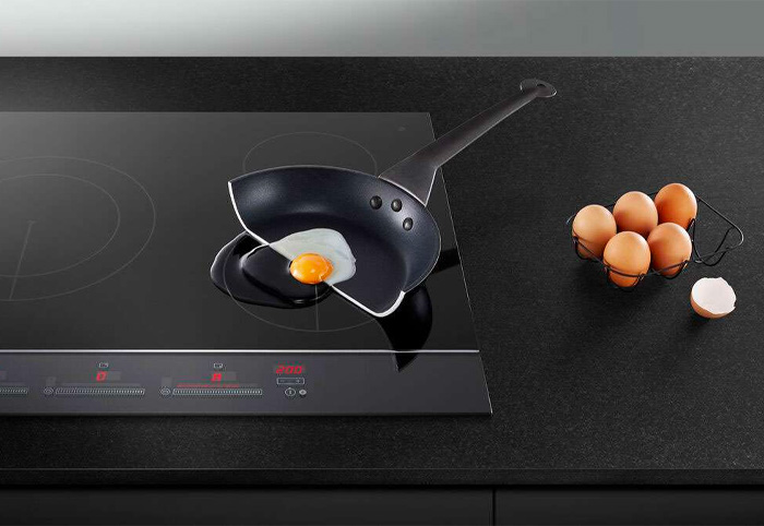 A pan with a cracked egg sits on a stovetop.