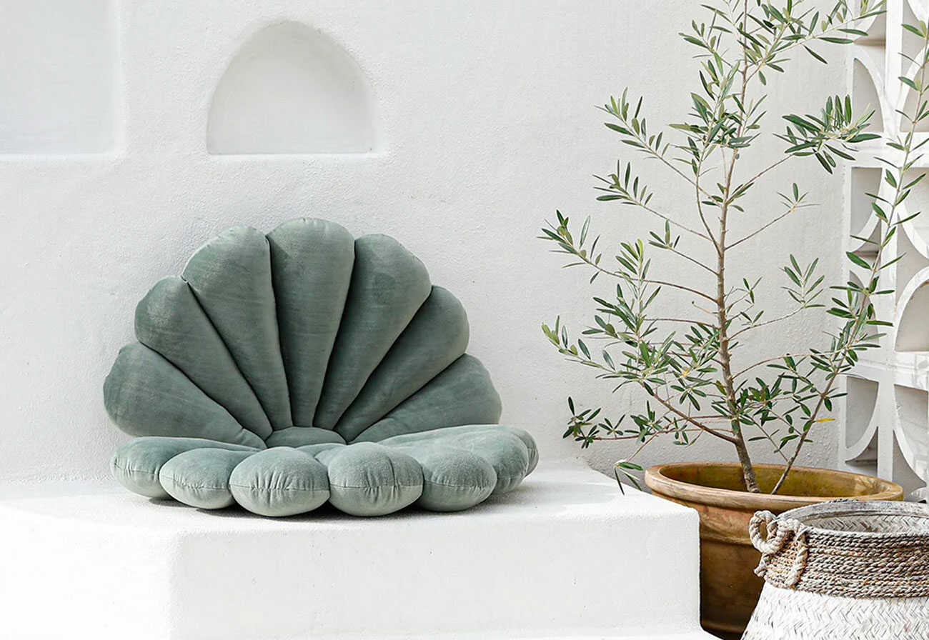 Green outdoor shell cushion on a white terrace.