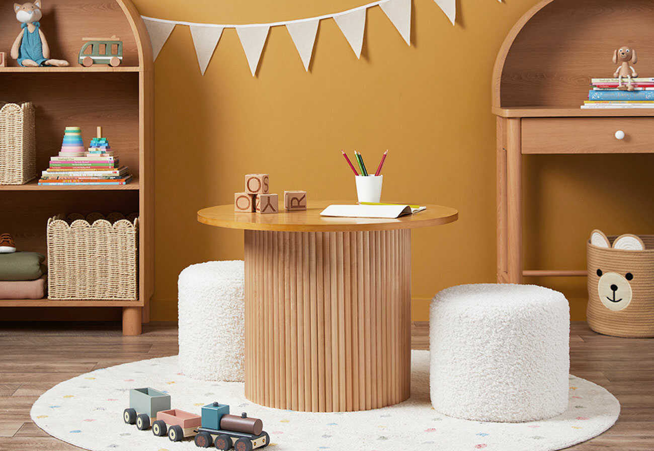 Children's wooden play table with two white boucle stools on either side. 