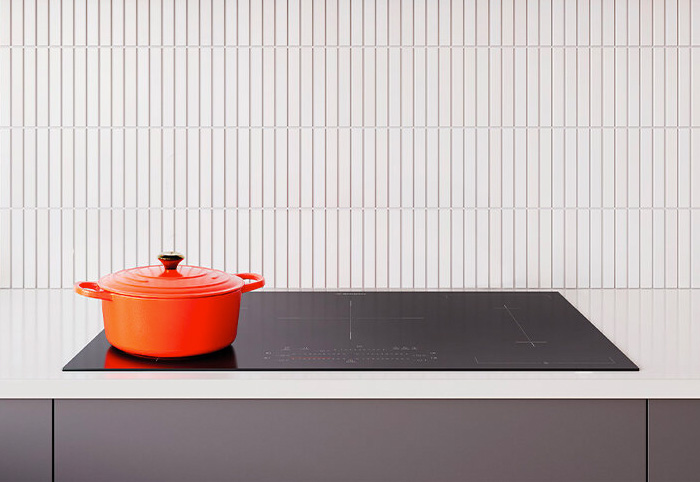 An orange dutch oven pot sits on a modern stovetop.