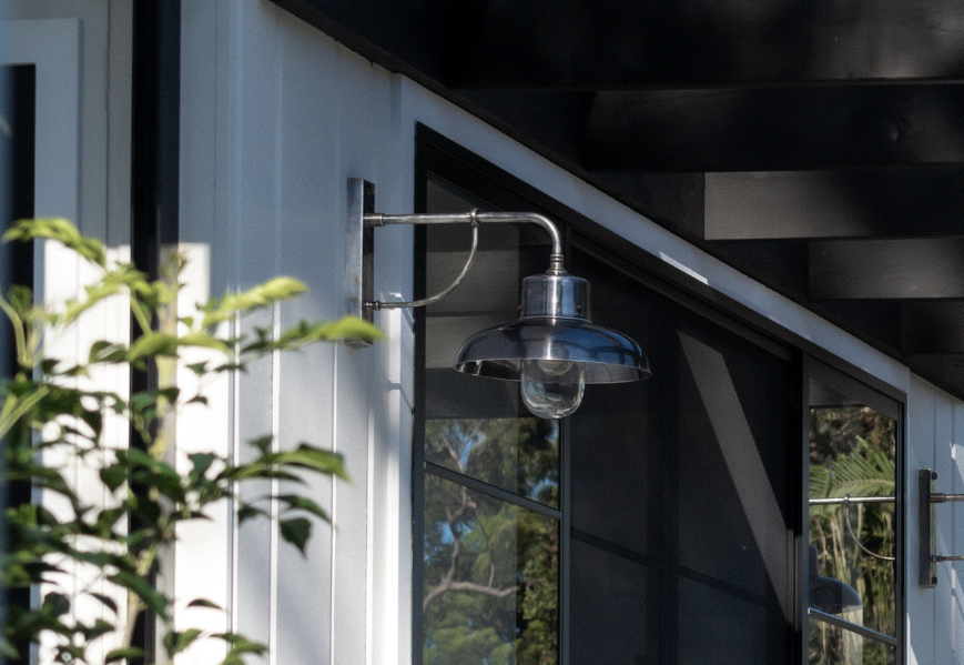 A silver barn light mounted on the side of a modern home.
