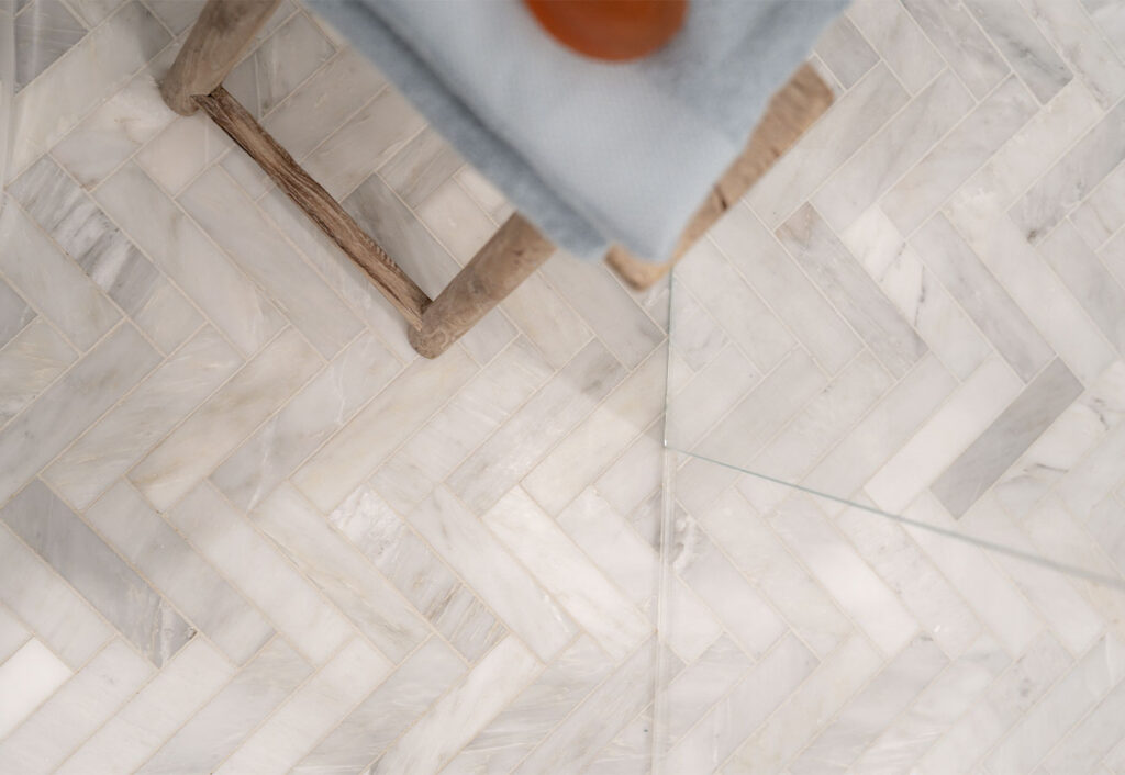 Thin rectangular herringbone tiles on a bathroom floor.