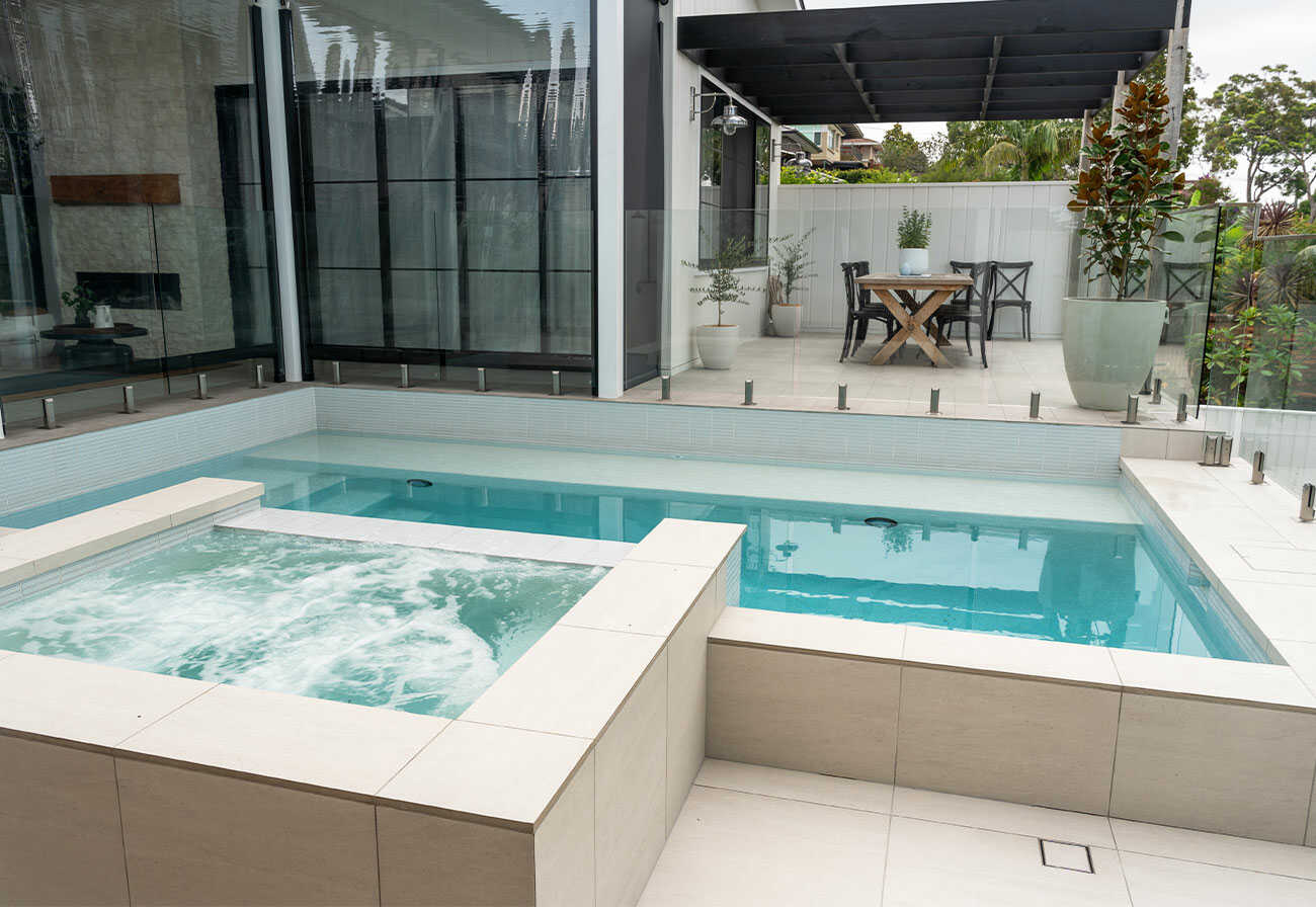 A modern pool and spa next to a covered alfresco area.