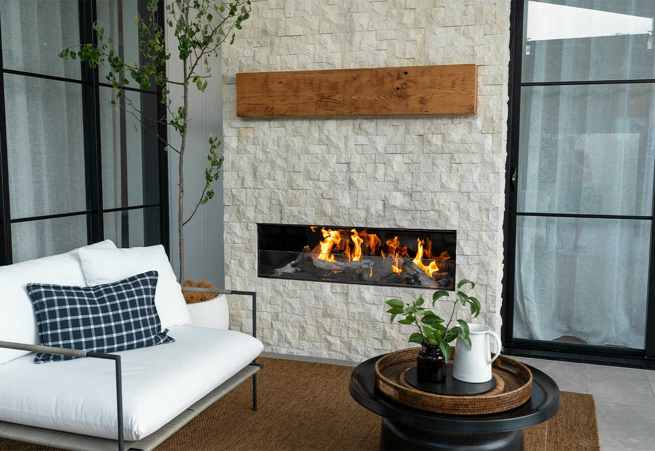 A wall-mounted outdoor fireplace in an alfresco area. 