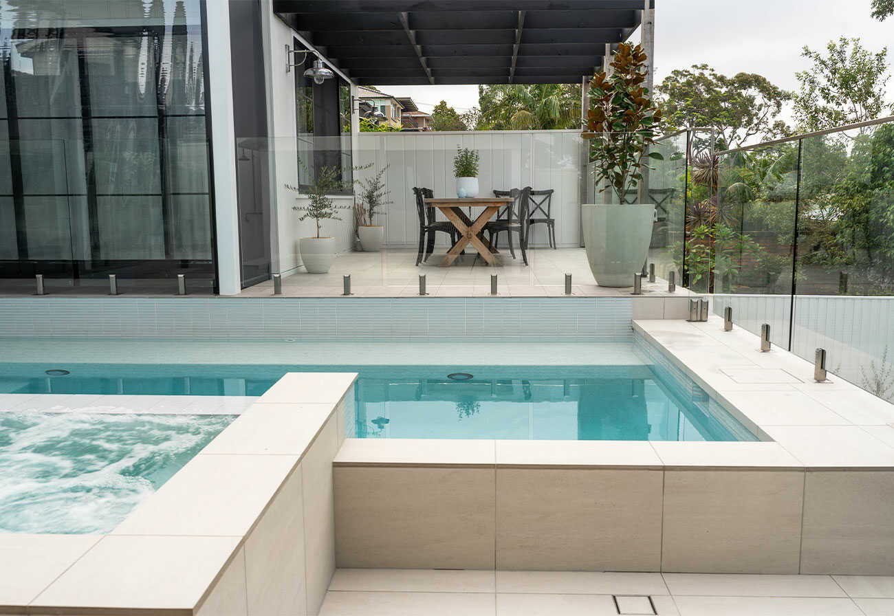 A modern swimming pool with a view to an outdoor dining area.
