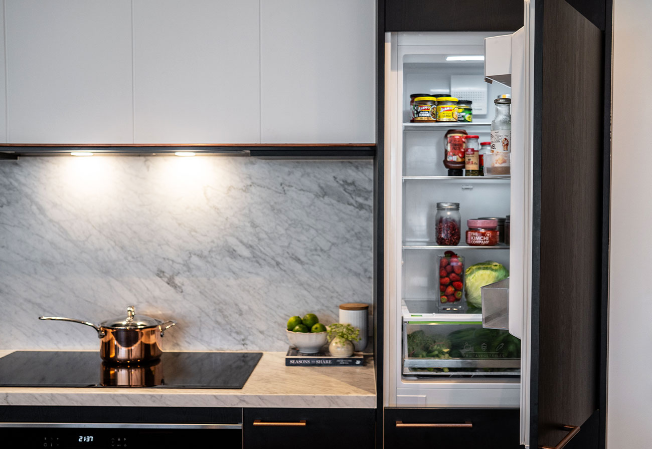 An open integrated fridge next to a cooktop.
