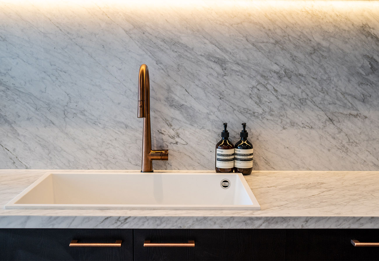 Marble kitchen benchtop with granite sink and copper tap.