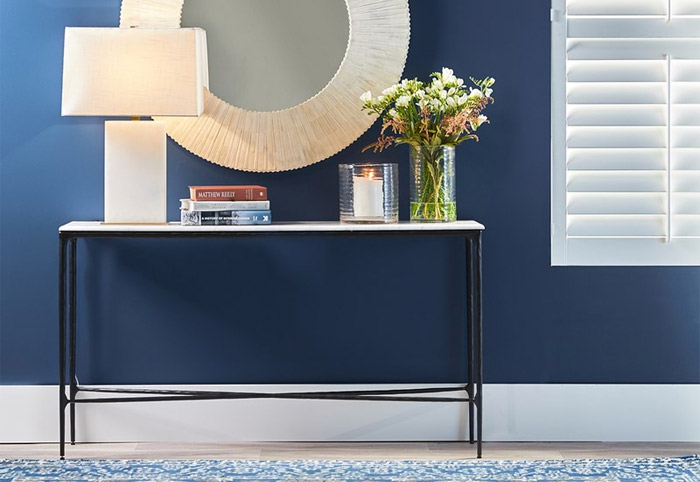 black marble top console table against a navy wall.