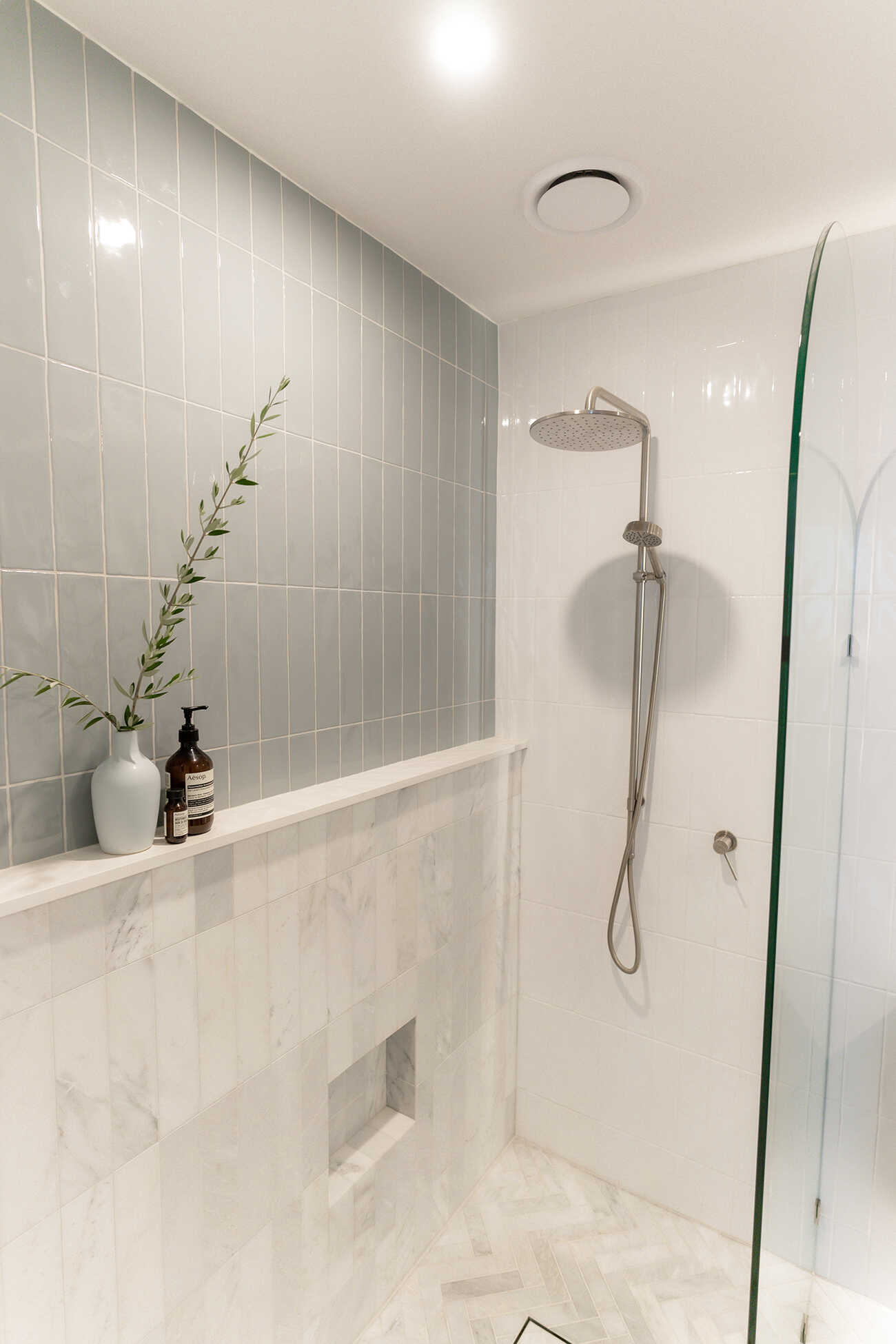 Modern open shower with arched glass and shower niche.