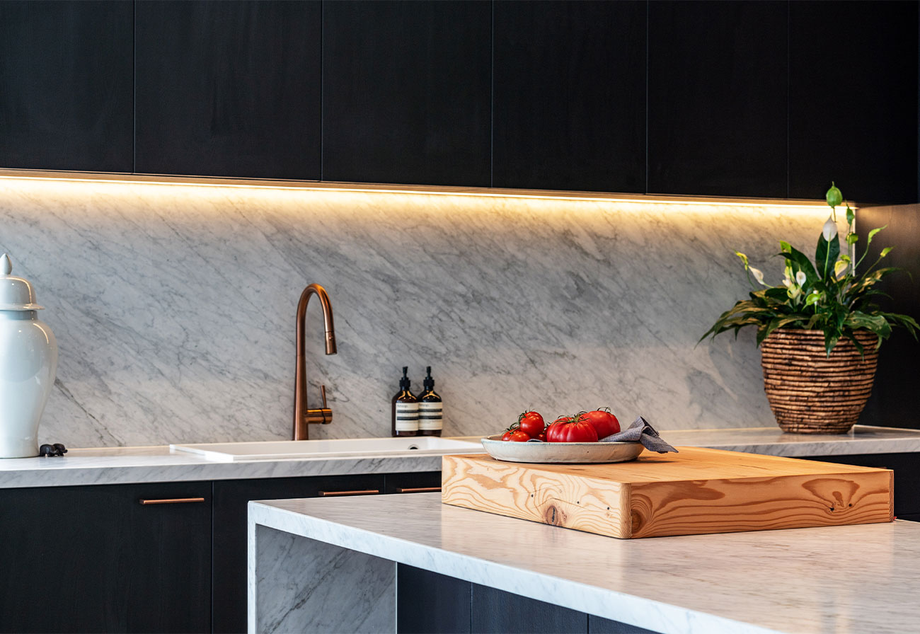 Bespoke budget kitchen renovation with dark cabinets and marble splashback.