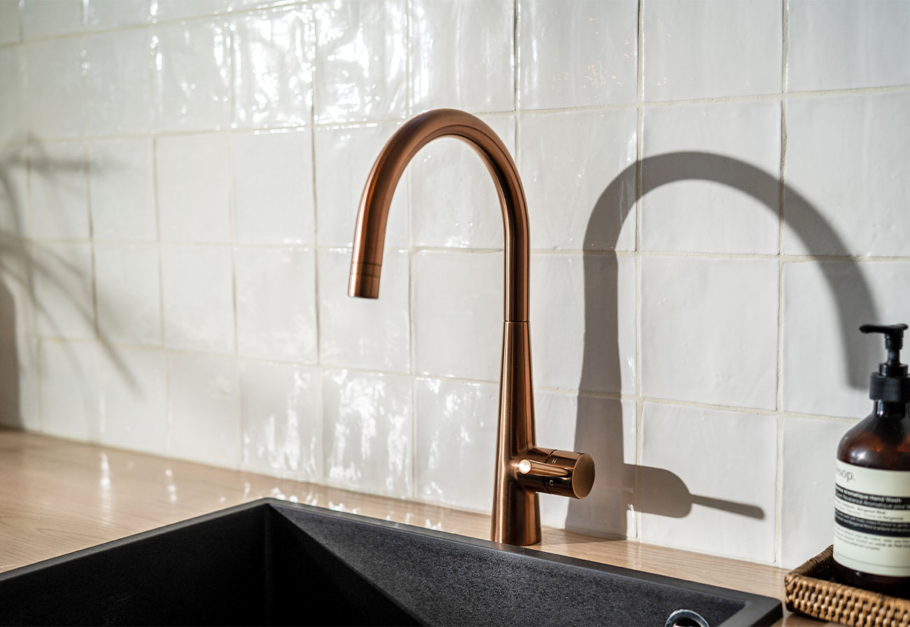 Brushed copper tap with a black granite basin.