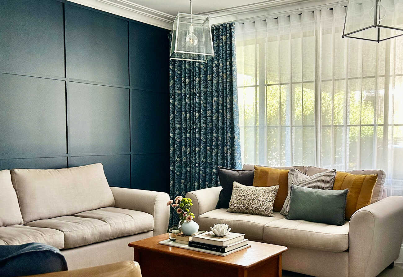 Media room with blue wall, beige sofa and sheer curtains.
