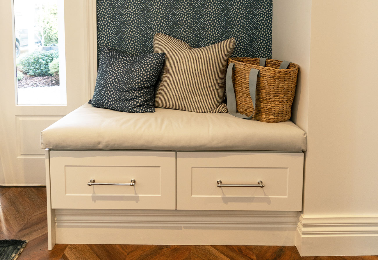 White entryway bench seat with two drawers underneath and padded seat top.