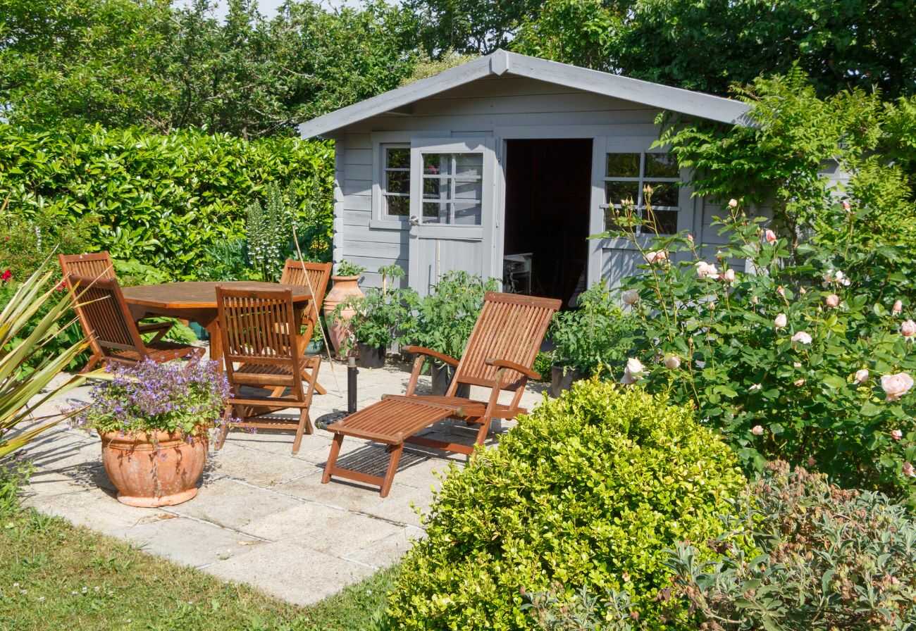 Grey garden shed with patio chairs out the front.