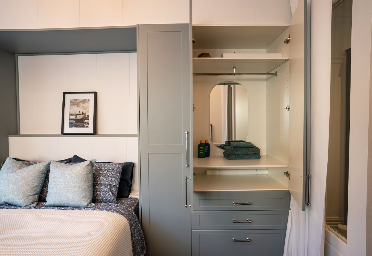 Open sage cabinetry in a guest bedroom.