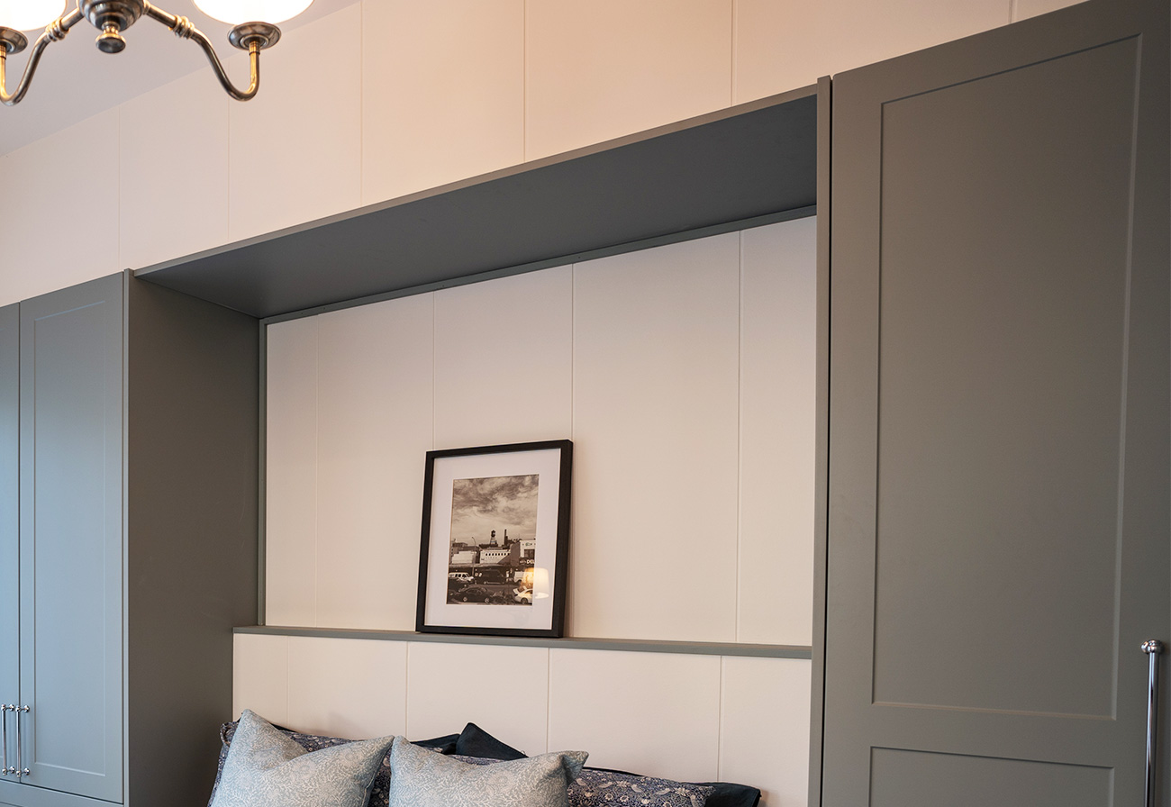Interior cladding above a wall bed in a guest bedroom.