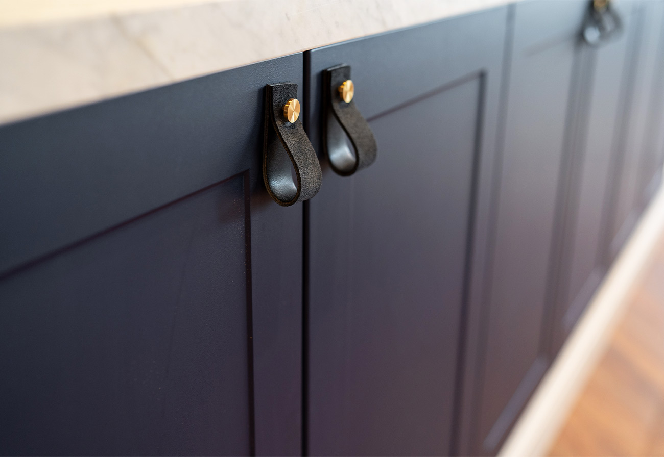 Handmade leather handles on a navy blue dining room buffet.