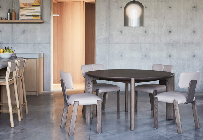 Round brown dining table in a modern family room with four chairs around it.